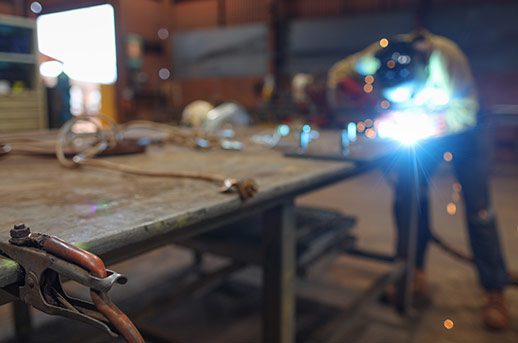 Isolated arc welder using earth clamp on the side table with defocused welder performing welding steel bolts