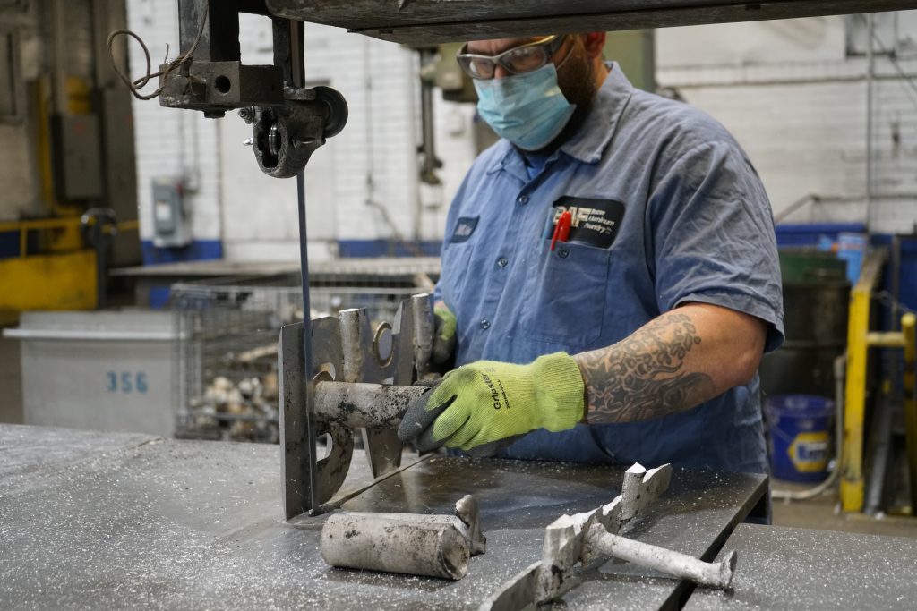 A quality control expert removes excess material from an aluminum casting