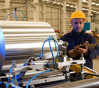 Factory worker processing roll of steel sheet